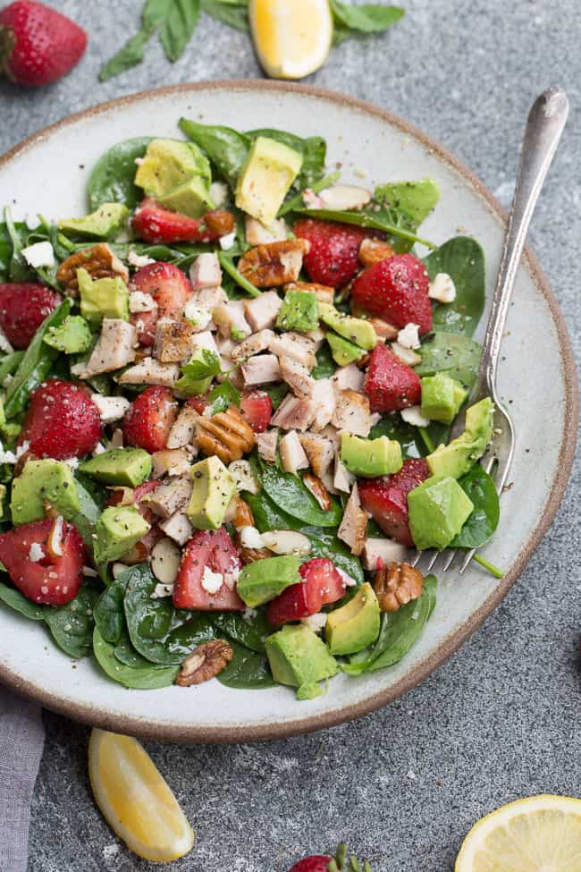Overhead view of a bowl of Strawberry Spinach Salad with Avocado, Chicken & Lemon Dressing