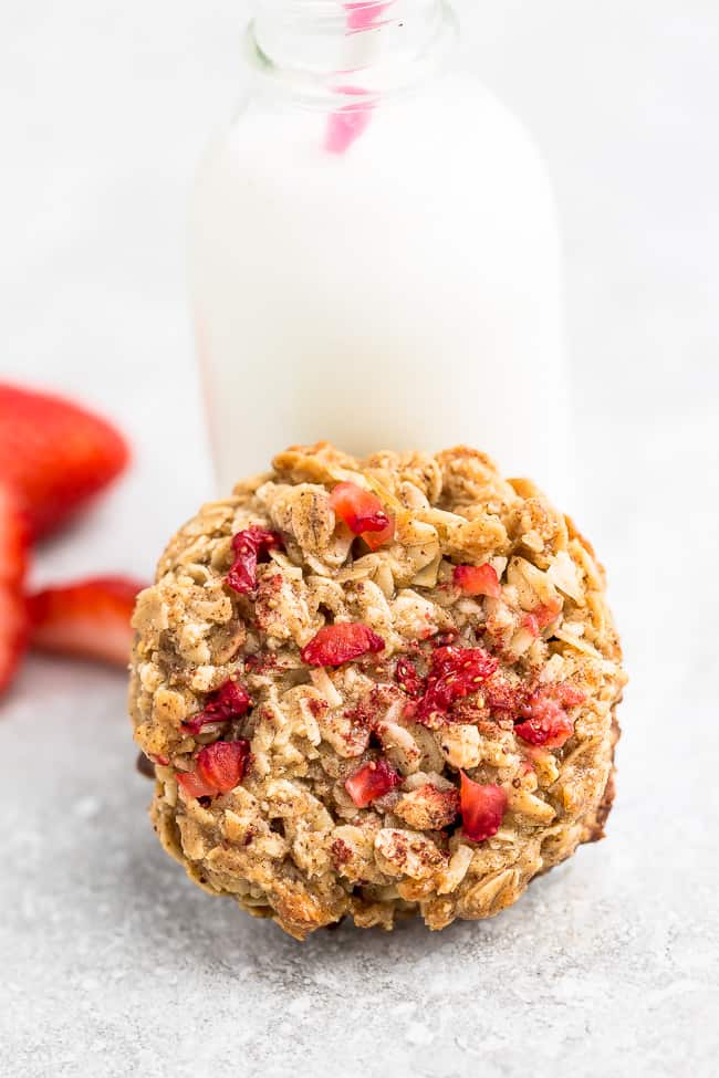 One Strawberry Cookie on a grey background leaning against a milk glass