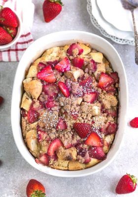 An overhead shot of a baked Strawberry French Toast Casserole in a white oval casserole dish
