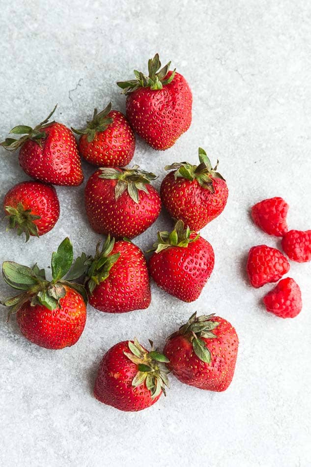 Top view of fresh strawberries and rasperries on a grey background