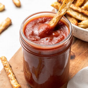 45 degree angle of homemade ketchup in a jar with a french fry dipped in the jar
