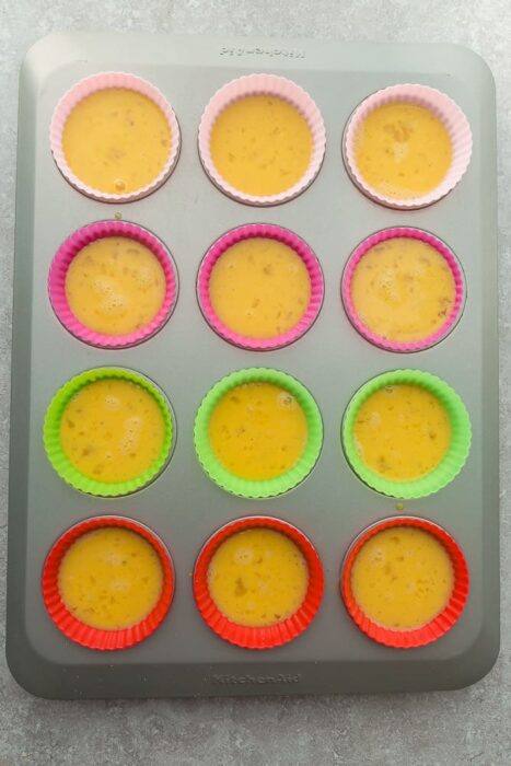 Top view of Muffin tin with silicone liners filled with egg mixture for breakfast egg muffins