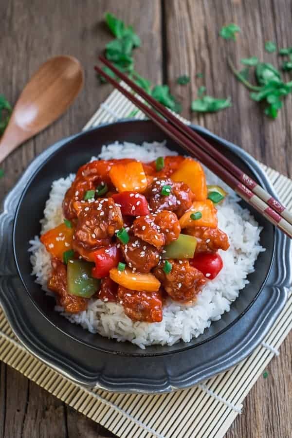Slow Cooker Sweet and Sour Chicken over fluffy white rice in a black bowl