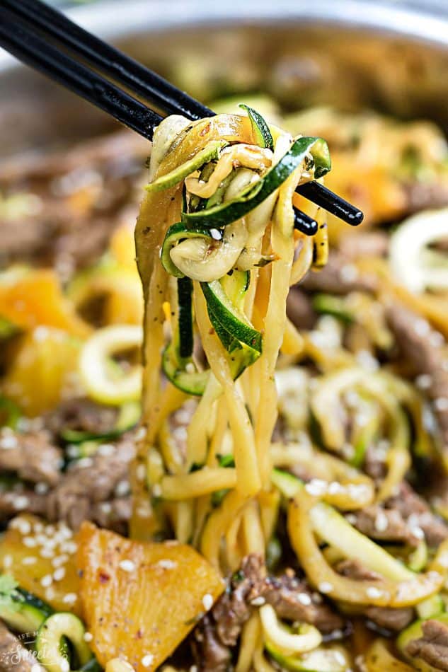 Zucchini Noodles on chopsticks over a skillet of Teriyaki Beef Stir-Fry