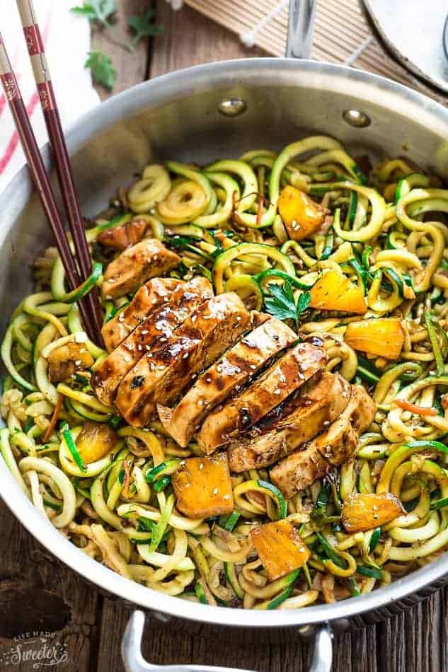 Spiralized zucchini noodles with teriyaki chicken and pineapples in a stainless steel pan.