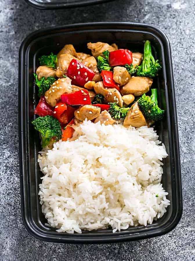 A storage container full of rice and stir-fried chicken, broccoli & bell peppers