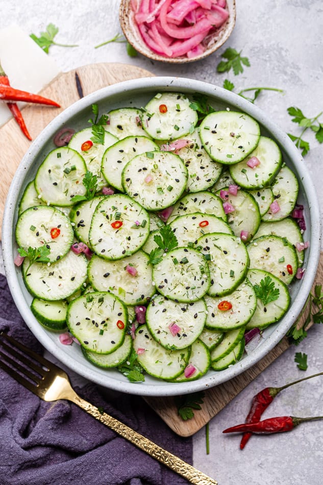 Overhead view of Cucumber Salad in a bowl with herbs
