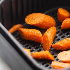Overhead view of sliced raw carrots in an air fryer basket