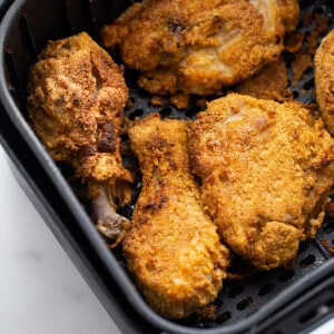 Four crispy fried chicken pieces in an air fryer basket