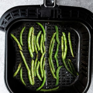 Air fried green beans inside of a large Air Fryer basket on top of a granite surface