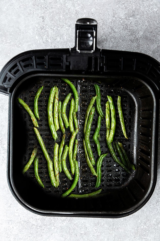 Air fried green beans inside of a large Air Fryer basket on top of a granite surface