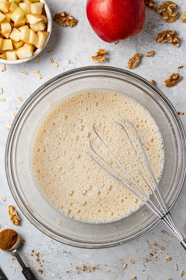 Mixed wet ingredients in a clear bowl with a whisk