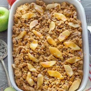 An entire apple french toast casserole in a blue rectangle baking dish on a grey background.