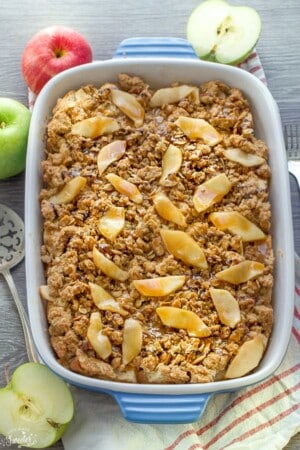 An entire apple french toast casserole in a blue rectangle baking dish on a grey background.