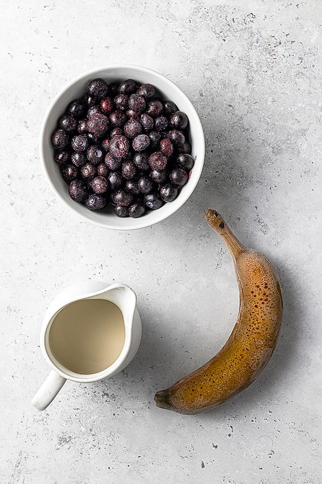 Ingredients to make a healthy cherry smoothie, frozen cherries, banana and almond milk