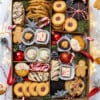 Flat-lay of a Holiday cookie box with holiday lights, candy canes and ornaments on a grey background