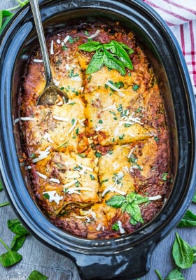 Layers of crock pot lasagna in a slow cooker pot with a spoon