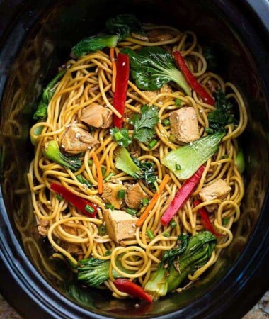Top view of crockpot lo mein in a black oval slow cooker.