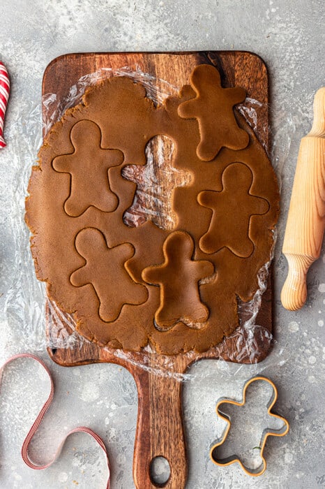 Top view of gluten free gingerbread men dough on a wooden cutting board with a rolling pin