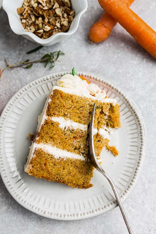 A slice of 3-layer Gluten Free Carrot Cake on a white plate with a fork