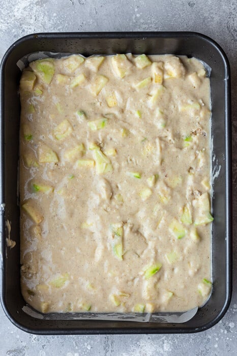 Overhead view of apple cake batter in a 9x13 pan
