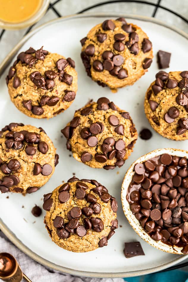 Top view of zucchini muffins on white plate with chocolate chips. 