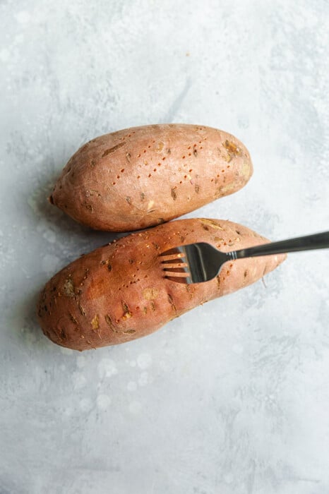 Fork piercing uncooked sweet potatoes