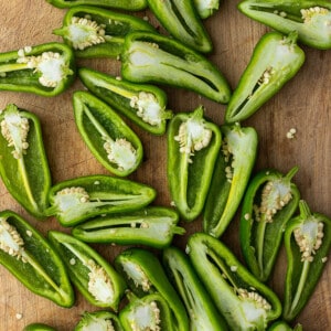 A batch of sliced jalapeño peppers on a wooden cutting board