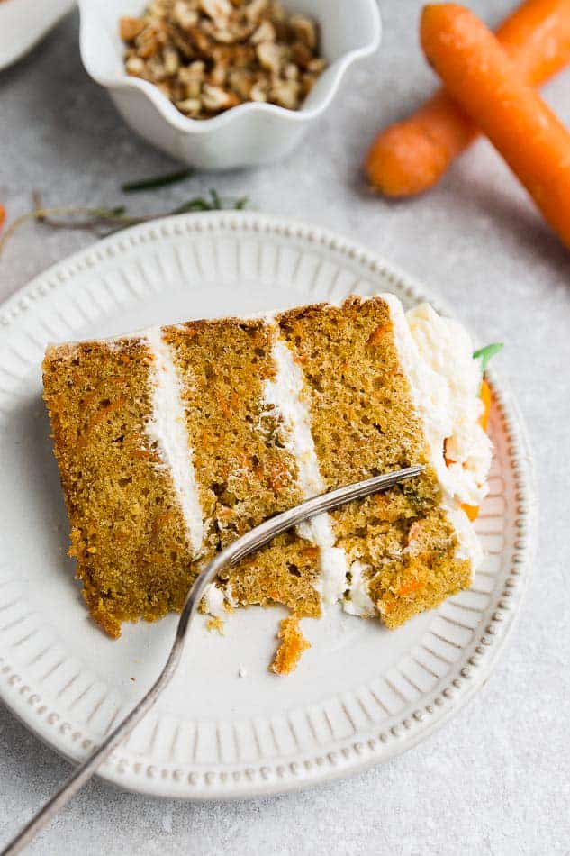 A slice of 3-layer Gluten Free Carrot Cake on a white plate with a fork