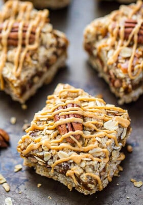 A peanut butter oatmeal bar topped with a whole pecan and a peanut butter drizzle