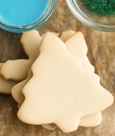 Top view of a stack of unfrosted Christmas tree sugar cookies on a wooden board