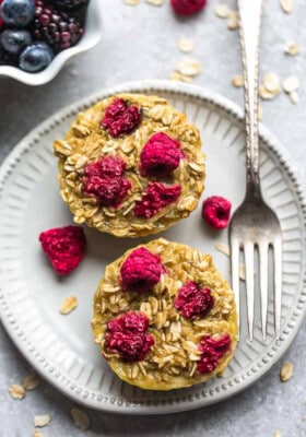 Two baked raspberry oatmeal cups on a white plate with a fork