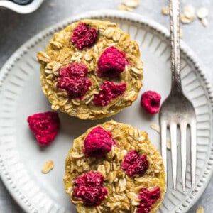 Two baked raspberry oatmeal cups on a white plate with a fork