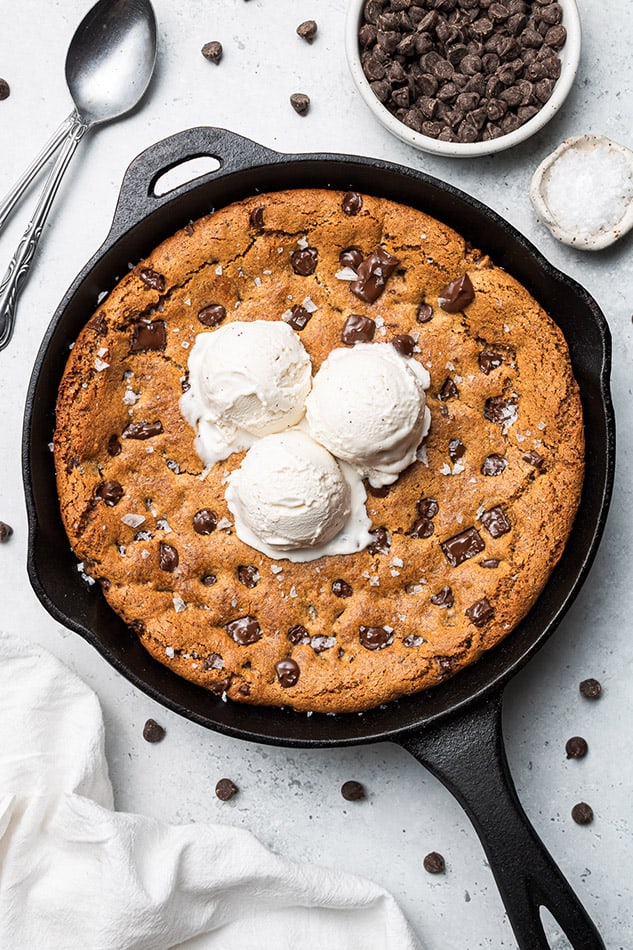 A chocolate chip cookie skillet with three scoops of vegan vanilla ice cream on top