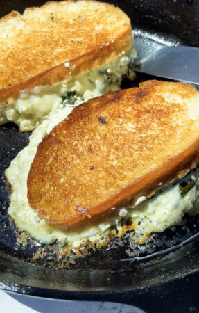 Two spinach grilled cheese sandwich melts on a hot buttered nonstick pan