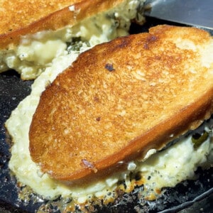 Two spinach grilled cheese sandwich melts on a hot buttered nonstick pan