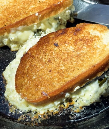 Two spinach grilled cheese sandwich melts on a hot buttered nonstick pan