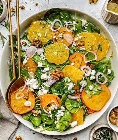 Spinach Orange Salad in a white bowl with gold serving spoons