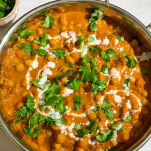 A batch of chickpea curry topped with fresh cilantro in a silver serving dish.