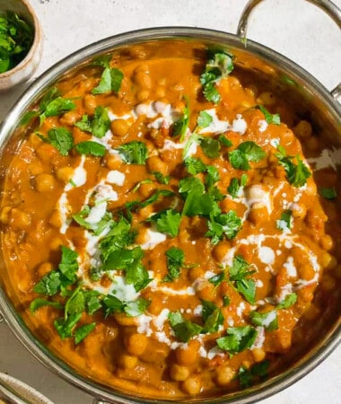 A batch of chickpea curry topped with fresh cilantro in a silver serving dish.