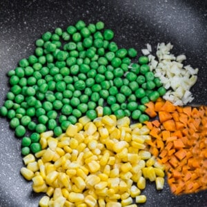 Peas, chopped carrots, corn and diced onions in a large skillet