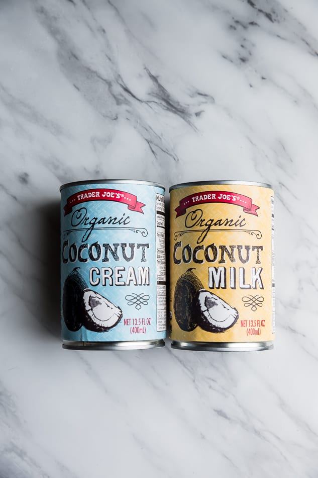 Top view of two cans of coconut cream and coconut milk from Trader Joe's on a white background