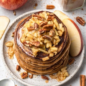 Overhead view of a stack of apple pancakes topped with chopped apples and pecans