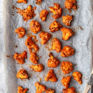 Top view of baked cauliflower wings on a baking sheet lined with parchment paper