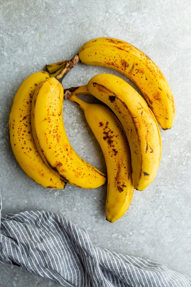 Top view of 5 spotty bananas on a grey background