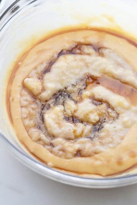 Close up view of banana cake batter in a clear mixing bowl