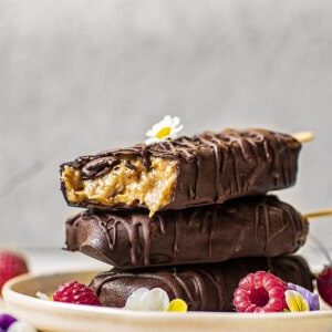 Side shot of a stack of 3 chocolate covered ice cream bars on a plate