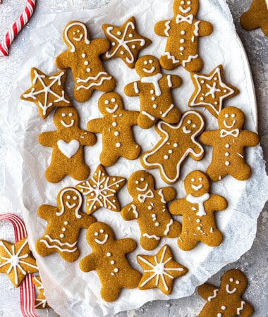 Top view of a pile of baked gluten free gingerbread men cookies on a white plate