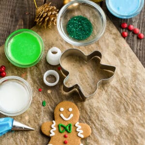 Top view of decorated vegan sugar cookies on a parchment paper on a wooden background with cookie cutters