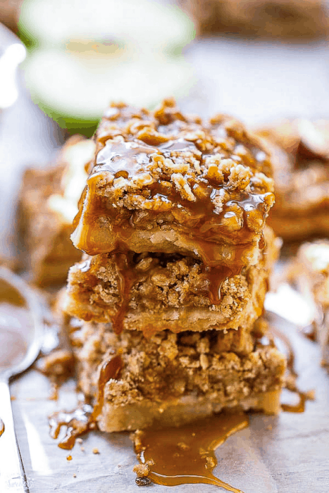Stack of three paleo vegan apple pie bars on a wooden cutting board
